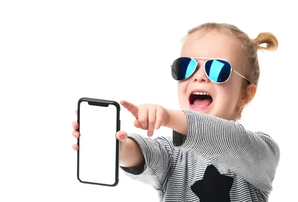 Niña niña en gafas de sol aviador azul mostrando pantalla en blanco de teléfono móvil gritando — Foto de Stock