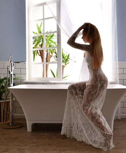 Young beautiful woman sitting near bathtub ready for taking bath near — Stock Photo, Image