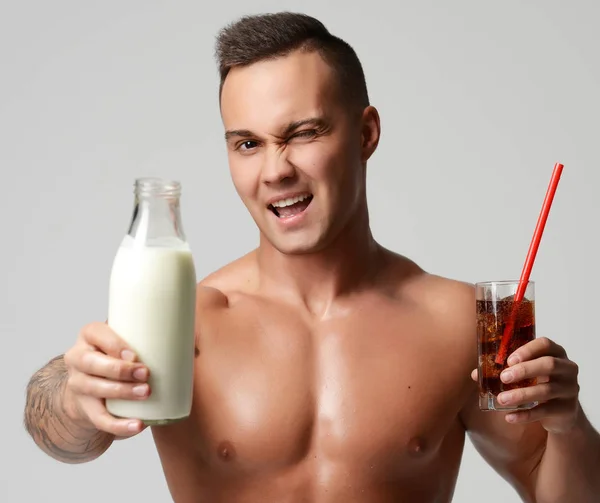 Retrato de atleta musculoso fuerte hombre mantenga la leche o kéfir comparar con soda —  Fotos de Stock