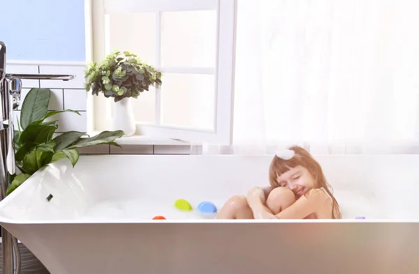 Happy little baby girl sitting in bath tub in the room — Stok Foto