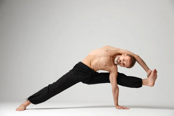 Mies harjoitellaan jooga klassinen Asana tanssi aiheuttaa seisoo käsillä — kuvapankkivalokuva