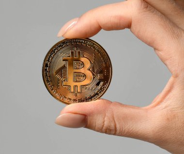 Elini tut altın bitcoin cryptocurrency gri arka plan üzerinde