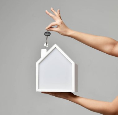 Emlak yatırım kavramı. Kadın elini tut ev ve Emlak para yatırım anahtar simgesi