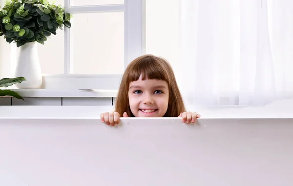 Glad liten baby flicka sitter i badkaret i badrummet — Stockfoto