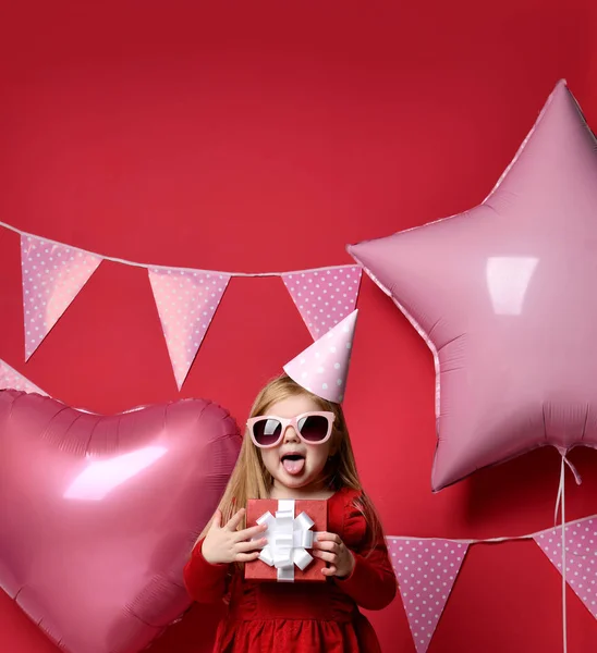 Очаровательная красивая девушка с розовыми шариками, красным подарком и кепкой на день рождения — стоковое фото