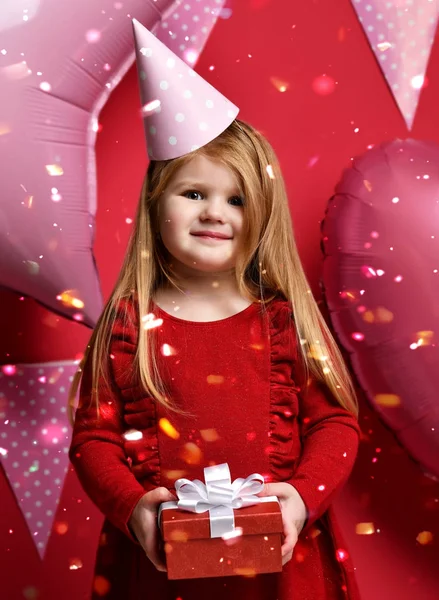 Menina bonita adorável com balões rosa e presente vermelho e boné de aniversário — Fotografia de Stock