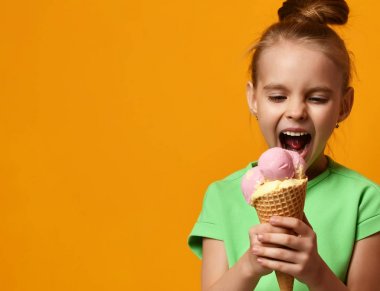 Güzel bebek kız çocuk yalama muz ve çilek dondurma waffle koni içinde yemek
