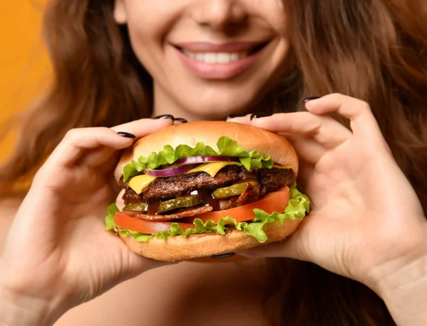 Kobieta jeść kanapkę burger z usta głodny na żółtym tle — Zdjęcie stockowe