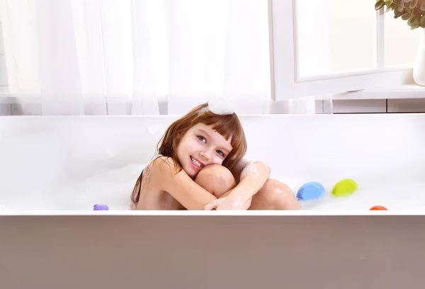 Glad liten baby flicka unge sitter i badkaret i badrummet — Stockfoto