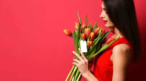 美丽的女人与花束郁金香花在红色的礼服和小贴纸在郁金香与自由的空白文本空间 — 图库照片