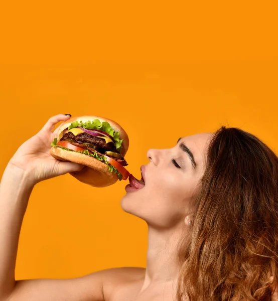 Frau essen Burger-Sandwich mit hungrigem Mund auf gelbem Hintergrund — Stockfoto