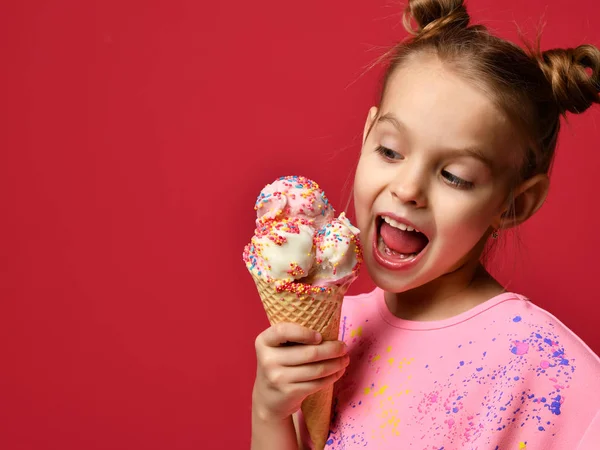 Pěkná holka dítě jíst, lízání velké zmrzliny v vafle kužel s malinovým šťastný smích — Stock fotografie