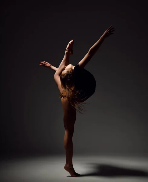 Jeune femme sportive gymnastique faire des exercices de fitness d'étirement à la salle de gym sombre — Photo