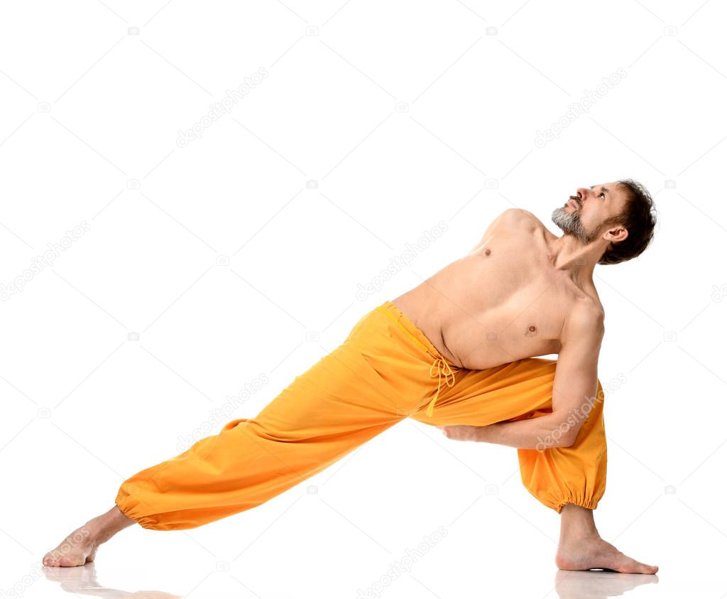 Old man practicing yoga doing sport stretching exercises in yellow pants 