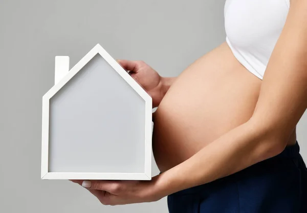 Gravid kvinna magen i vit topp skjorta hålla lilla huset — Stockfoto