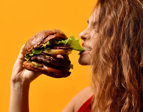 Woman eat burger sandwich with hungry mouth on yellow background — Stock Photo, Image