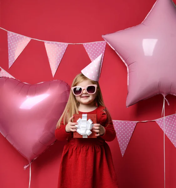 Adorabile bella ragazza con palloncini rosa e rosso regalo e cappello di compleanno — Foto Stock