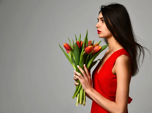 Красива жінка з букетом квітів тюльпанів у червоній сукні та маленькою наклейкою на тюльпани — стокове фото
