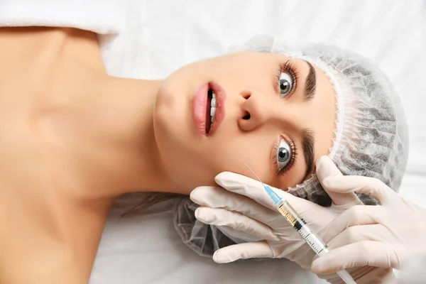 Plastik cerrahi güzellik kavramı genç esmer kadın yüz ve doktor şırınga ile el olarak eldiven — Stok fotoğraf