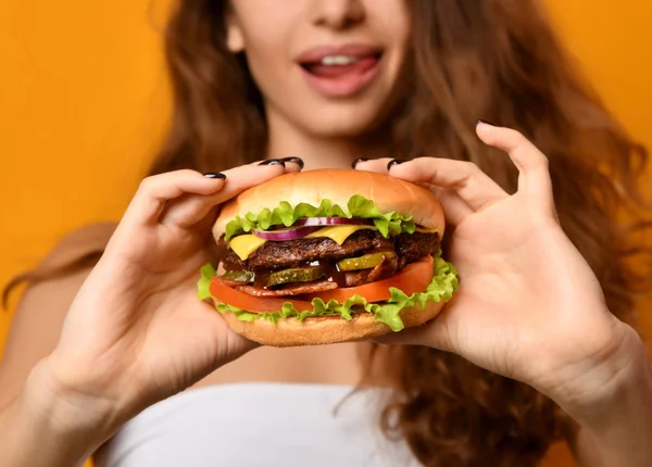 Woman eat burger sandwich with hungry mouth on yellow background — Stock Photo, Image