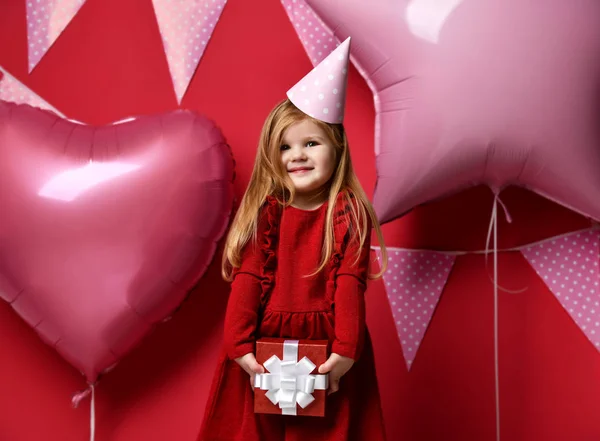 Adorable pretty girl with pink balloons and red present gift and birthday cap — Stock Photo, Image