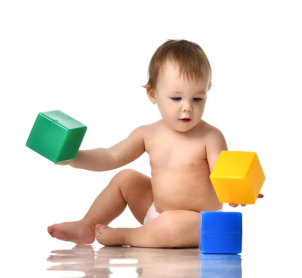 Infant child baby girl toddler playing holding green blue yellow bricks toys — Stock Photo, Image