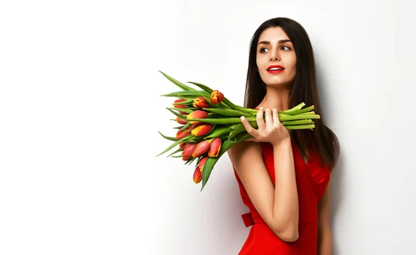 Hermosa mujer con ramo de flores de tulipán en vestido rojo y pequeña pegatina en tulipanes —  Fotos de Stock
