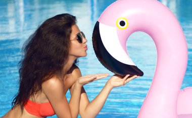 Genç seksi kadın dev şişme dev pembe flamingo float öpüşme yüzme havuzunda güzel