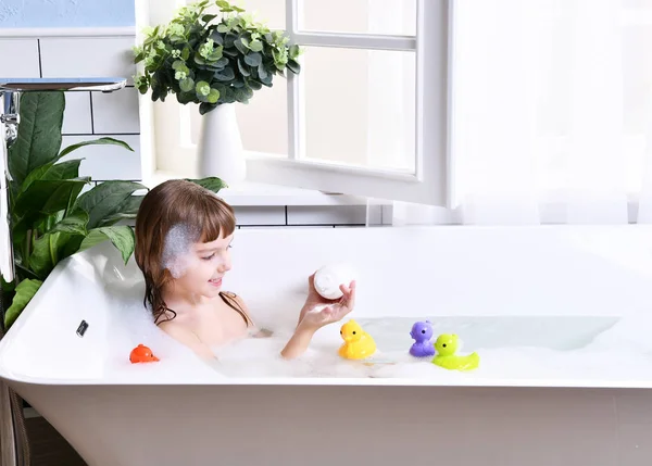 Feliz niña pequeña niña sentada en la bañera en el baño —  Fotos de Stock