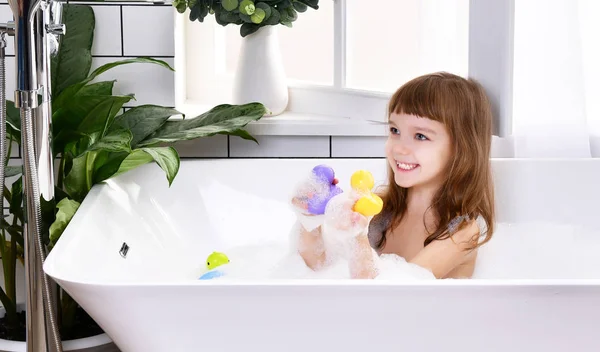 Feliz niña pequeña niña sentada en la bañera en el baño — Foto de Stock