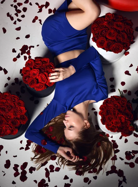 Woman lying on red lips sofa couch in blue dress smiling with roses bouquet flowers petals — Stock Photo, Image