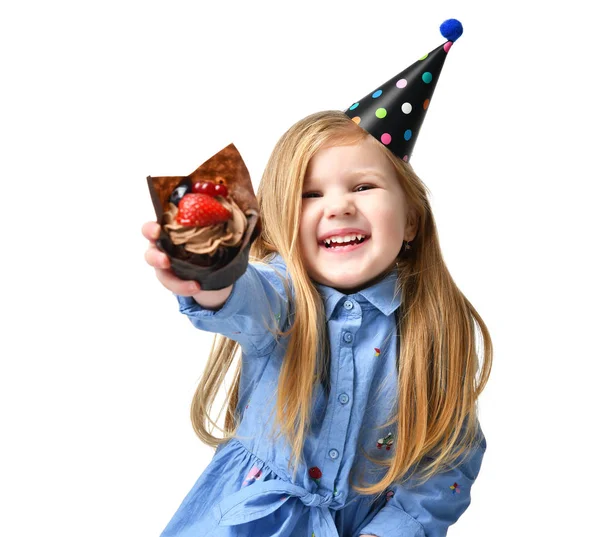 Tre anni ragazza bambino mangiare dolce torta di cioccolato muffin con frutta che celebra in cap compleanno isolato — Foto Stock