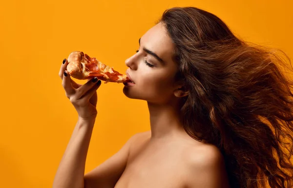 Молодая красивая женщина есть пиццу пепперони ломтик и держать целую пиццу в коробке — стоковое фото