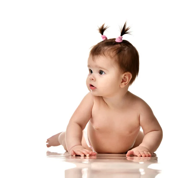 Infant child baby girl lying naked in diaper on the floor and looking at the corner — Stock Photo, Image