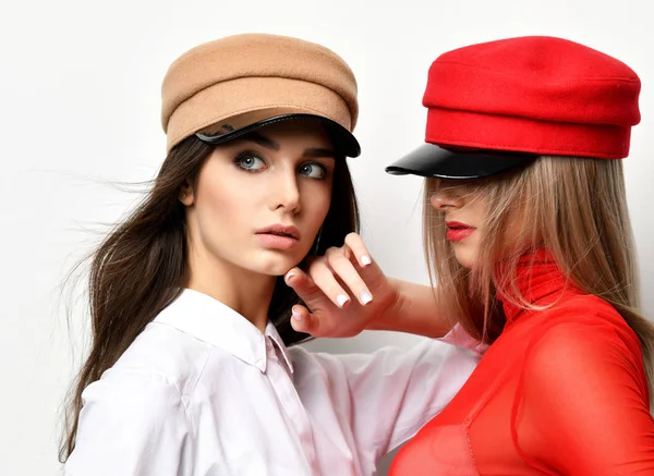 Two young sexy brunette woman in red and brown peaked cap together — Stock Photo, Image