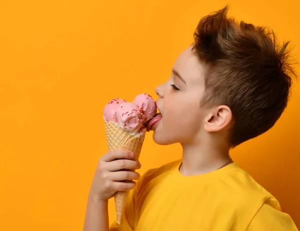 黄色のワッフル コーンにストロベリー アイス クリームをなめるを食べる赤ちゃん男の子子供 — ストック写真