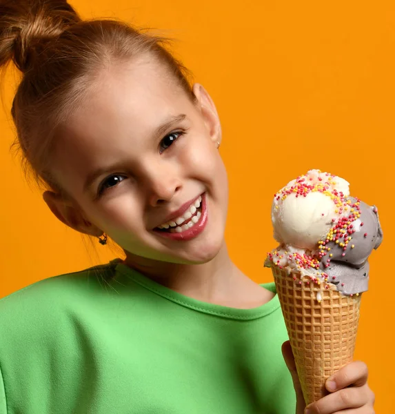 Pretty baby girl kid eating licking vanilla ice cream in waffles cone ...