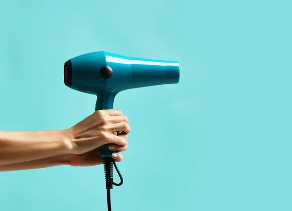 Woman hands hold blue hair dryer on mint blue — Stock Photo, Image