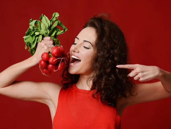 Piuttosto allegra giovane donna sportiva tenere ravanello fresco con foglie verdi e dito puntato. Dieta — Foto Stock