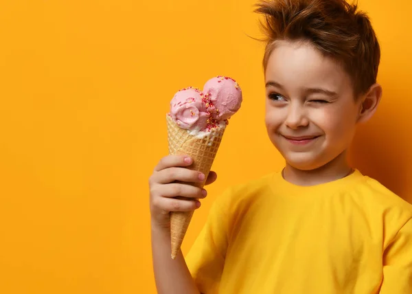 Bebé niño comiendo helado de fresa en gofres cono y guiño en amarillo —  Fotos de Stock