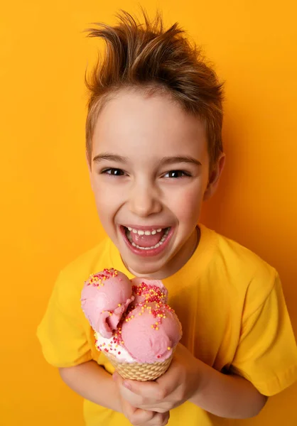 Малыш ест клубничное мороженое в вафельном рожке счастливо улыбаясь смеясь — стоковое фото