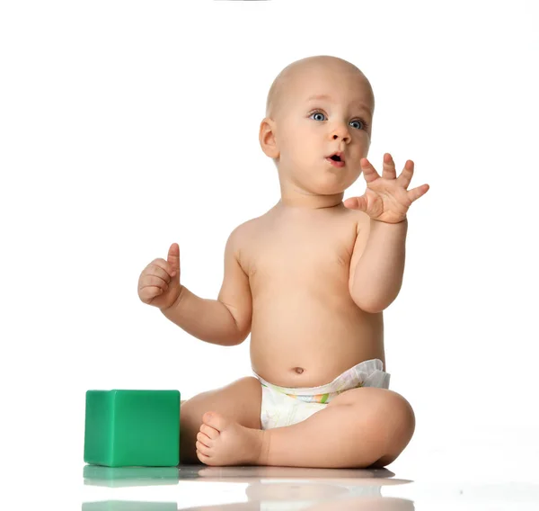 Infant child baby boy toddler sitting naked in diaper with green brick toy looking up — Stock Photo, Image