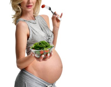 Güzel hamile kadın organik salata ve domates çatalla tutun. Hamilelik annelik beklentisi sağlıklı beslenme 