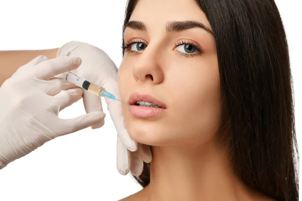 Cirugía de labios plásticos concepto de belleza joven morena cara y médico mano en guante con jeringa —  Fotos de Stock