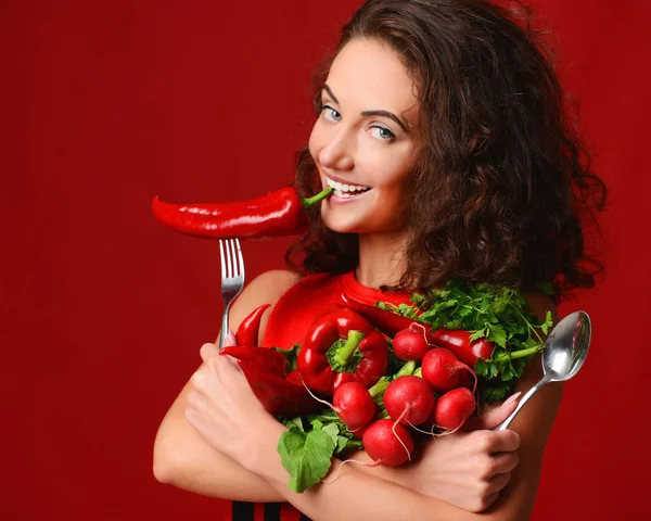 Hezká mladá žena pózuje s čerstvou zeleninou červené ředkvičky chilli papričky zelené listy salátu petržel vidlička a lžíce — Stock fotografie