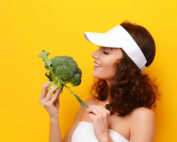 Jovem mordida mulher grande verde fresco brócolis vegetal em chapéu branco . — Fotografia de Stock