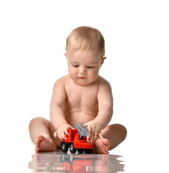 Infant child baby boy toddler sitting naked in diaper playing with red car toy — Stock Photo, Image