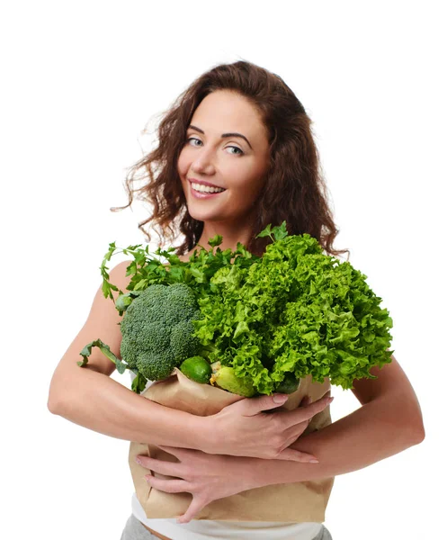 Une jeune femme tient un sac d'épicerie plein de légumes verts frais — Photo