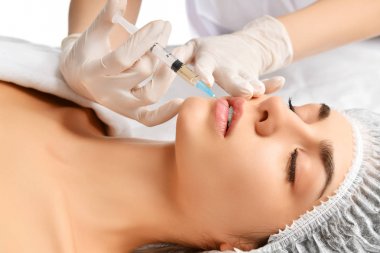 Plastik dudak ameliyatı güzellik kavramı genç esmer kadın yüz ve doktor şırınga ile el olarak eldiven