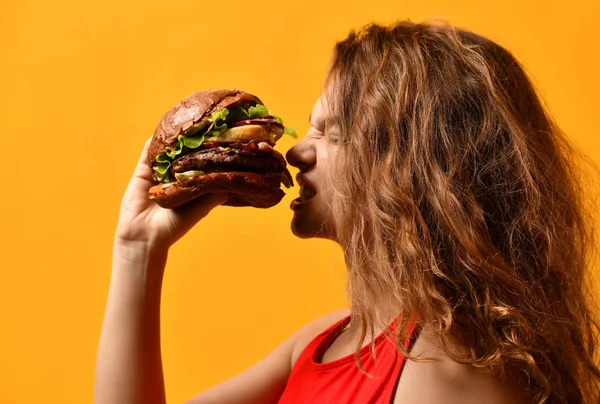 Frau essen Burger-Sandwich mit hungrigem Mund auf gelbem Hintergrund — Stockfoto